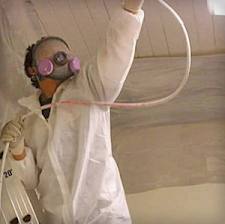 Mold remediation technician wearing full personal protective equipment including respirator, coveralls, gloves, and goggles